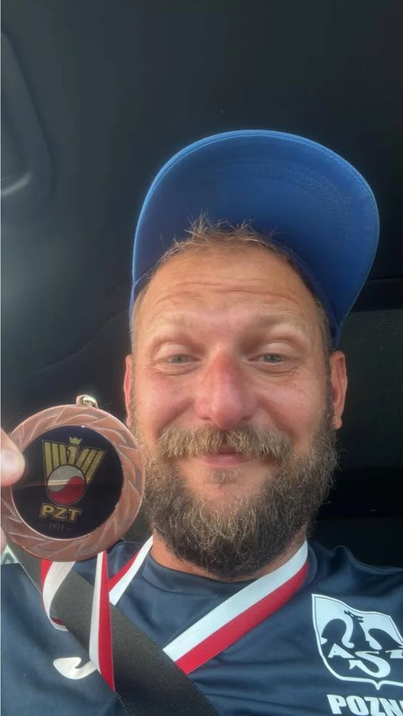 Jeremiasz Radwan w koszulce AZS Poznań pokazuje brązowy medal Polskiego Związku Tenisowego